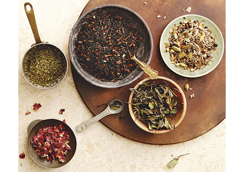 Three bowls and two measuring cups with tea and herbs.