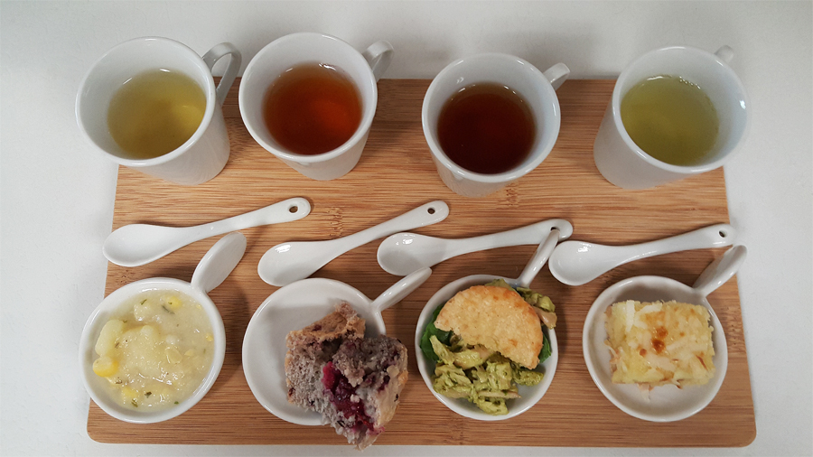 Four teacups of tea and four small plates with different foods.