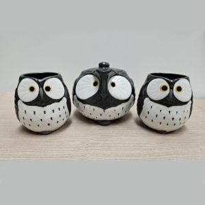 Small owl-shaped teapot and two owl-shaped teacups, black with white bellies.