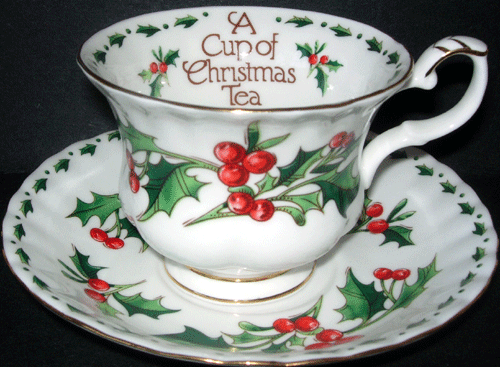 White teacup and saucer with holly leaves and holly berry design, words inside the cup "A Cup of Christmas Tea."